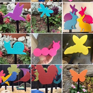 May include: A collection of colorful garden stakes featuring various animal and insect designs. The stakes include a purple hummingbird, blue dragonfly, pink caterpillar, yellow butterfly, and more. Each stake is mounted on a black metal rod.