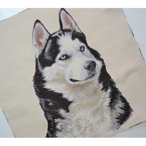 May include: A woven textile featuring a detailed portrait of a Siberian Husky dog. The dog has striking blue eyes, black and white fur, and a cream-colored background. The image is a close-up of the dog's head and shoulders.