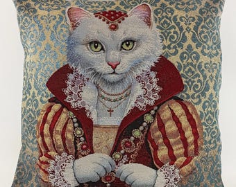 May include: A white cat dressed in a red and gold embroidered robe with a white lace collar and a pearl necklace. The cat is wearing a crown and has a jeweled pendant around its neck. The background is a blue and gold damask pattern.