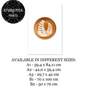 May include: A print featuring a latte art design with two leaf patterns in a brown cup. The print is on a white background with the Studio Pica Prints logo in the upper left corner. Available in various sizes.