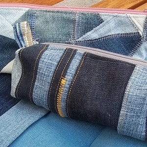 Könnte beinhalten: Zwei Reißverschlusstaschen aus Jeans, eine mit geometrischem Muster und die andere mit einem Streifenmuster. Beide Taschen sind aus recyceltem Jeansstoff gefertigt und haben einen Reißverschluss.