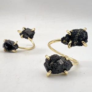 May include: Two gold rings with black stones. The rings are twisted and have a unique design.