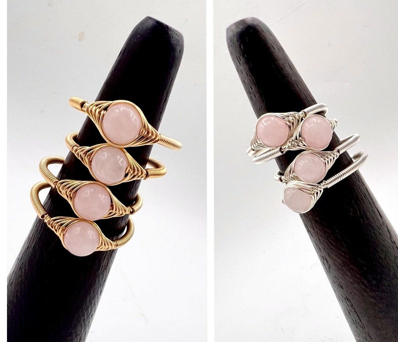 May include: Two sets of stacked rings with pink stones wrapped in wire. One set is gold and the other is silver.