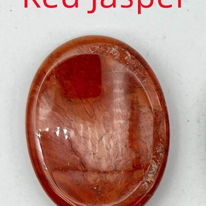 K&ouml;nnte beinhalten: Roter Jaspis-Handstein mit einer glatten, polierten Oberfl&auml;che und einem wirbelnden rot-wei&szlig;en Muster.