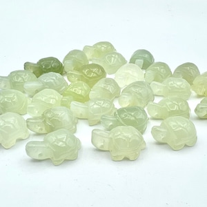 May include: A collection of small, carved jade turtle figurines. The turtles are a pale green color and have a smooth, polished finish.