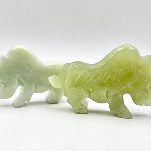 May include: Two jade green ox figurines, one is a lighter shade of green than the other. Both are carved in a traditional style with detailed features.