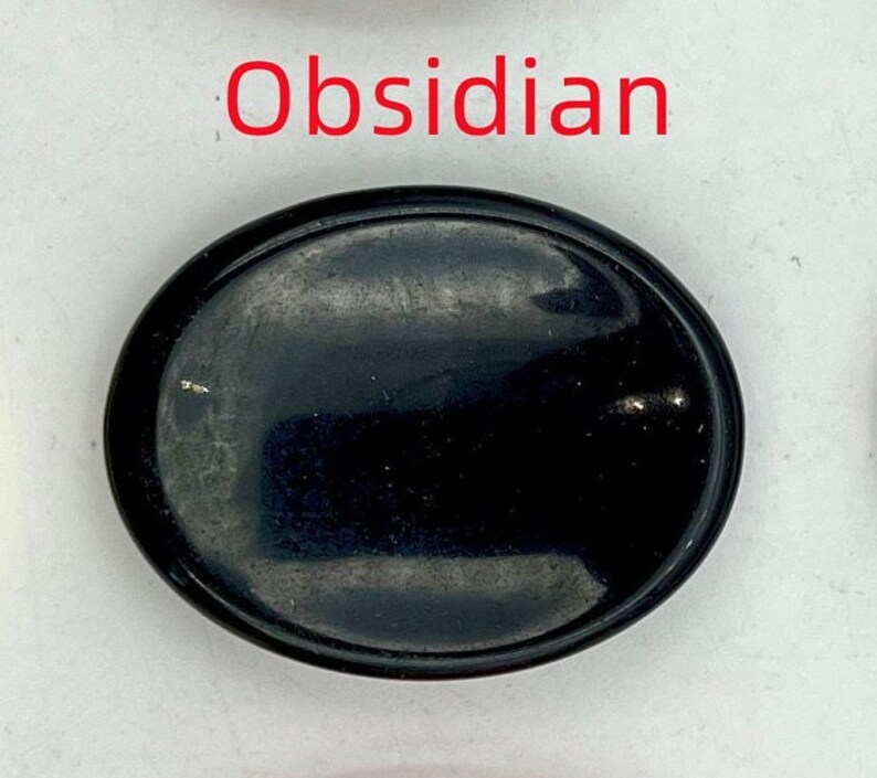 K&ouml;nnte beinhalten: Ovaler Obsidian-Stein mit glatter, polierter Oberfl&auml;che. Der Stein ist schwarz und hat einen leichten Glanz.