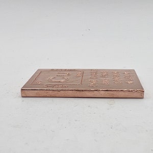 以下が含まれることがあります： 化学記号「Cu」と「One Ounce Fine Copper 99.9% Pure」という刻印が施された銅の棒です。