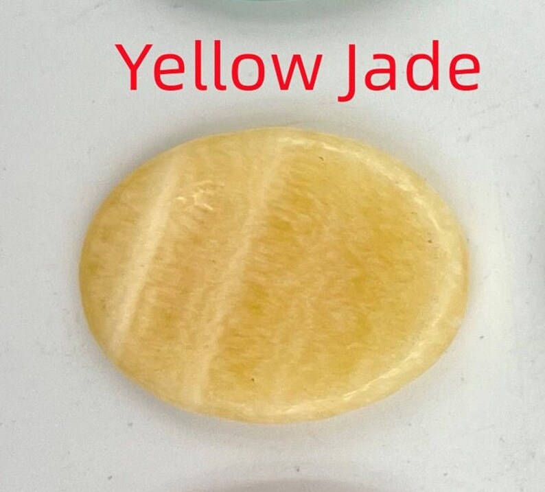 K&ouml;nnte beinhalten: Ein glatter, ovaler gelber Jadestein mit hellgelber Farbe und wei&szlig;en Streifen.