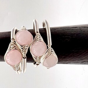 May include: Three silver wire wrapped rings with pink rose quartz stones.