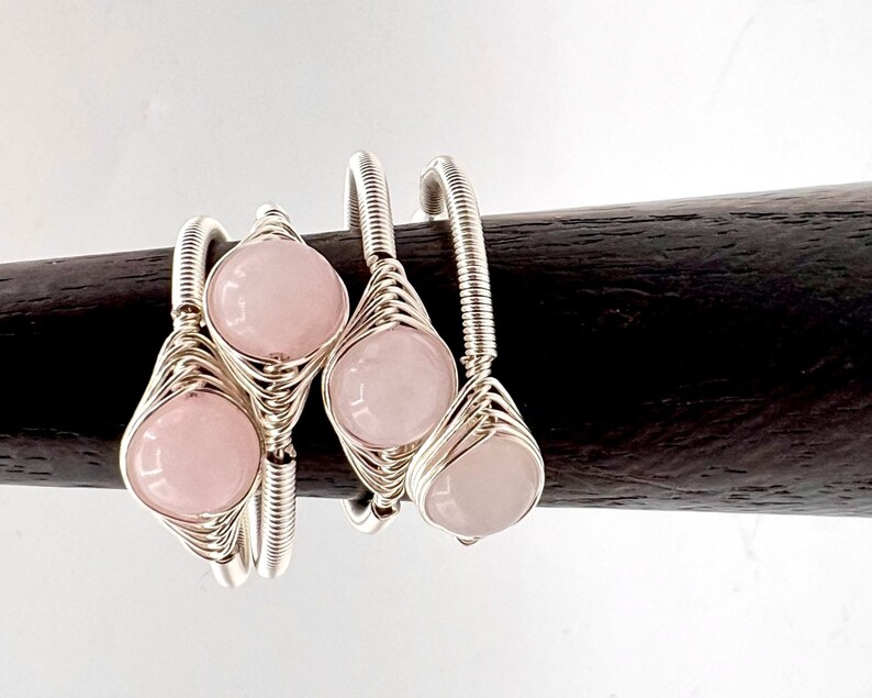 May include: Three silver wire wrapped rings with pink rose quartz stones.