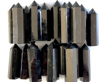 May include: A collection of twenty black obsidian crystal points, also known as black glass, arranged in two rows. The points are smooth and polished, with a sharp tip and a flat base.