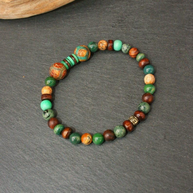 May include: A green, brown, and gold beaded bracelet with a decorative metal bead.