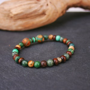 May include: A green, brown, and gold beaded bracelet with a decorative metal bead.