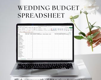 May include: A laptop computer displaying a wedding budget spreadsheet on the screen. The spreadsheet has columns for item, total cost, amount already paid, and total owing. The laptop is on a white surface with a white flower in the background.