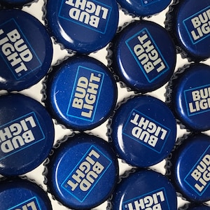 May include: A close-up of multiple blue bottle caps with the text "Bud Light" printed in white.