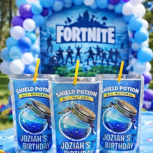 May include: Three blue pouches with yellow straws, labeled "Shield Potion All Natural" and "Joziah's 7th Birthday." A Fortnite-themed backdrop with balloons and the game's logo is visible. The pouches feature a blue potion design.
