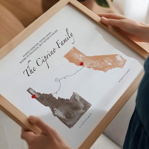 May include: A framed print featuring two watercolor-style state maps, California in tan and Idaho in grey, connected by a dotted line with a heart. The text reads The Ciprino Family and Family forever, never apart, maybe in distance, but never in heart.
