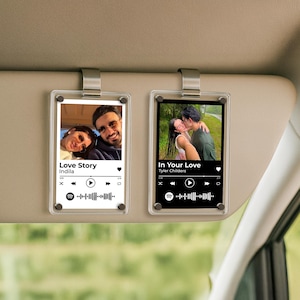 May include: Two clear acrylic car visor clips with photos and music player interfaces. One displays a photo with the text "Love Story" and the other "In Your Love". Both have a Spotify logo and a play bar.