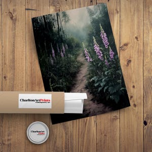 Puede incluir: Una impresi&oacute;n enrollada y una impresi&oacute;n de un sendero forestal con flores moradas. La impresi&oacute;n est&aacute; en un tubo marr&oacute;n con una etiqueta blanca que dice "Charlton Art Prints contemporary art". Tambi&eacute;n es visible un peque&ntilde;o recipiente redondo con el mismo logotipo.