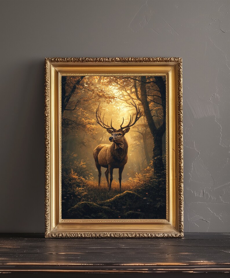 May include: A framed painting of a red deer standing in a forest. The deer has large antlers and is looking directly at the viewer. The forest is filled with trees and leaves, and the light is shining through the trees. The painting is in a gold frame.