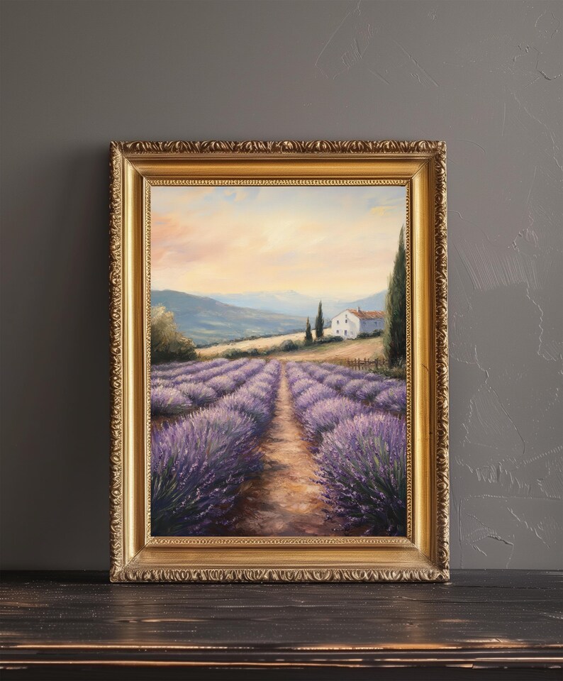 May include: A framed oil painting depicting a landscape with a white farmhouse in the distance, surrounded by rows of purple lavender flowers. The painting has a golden frame and is set against a gray background.