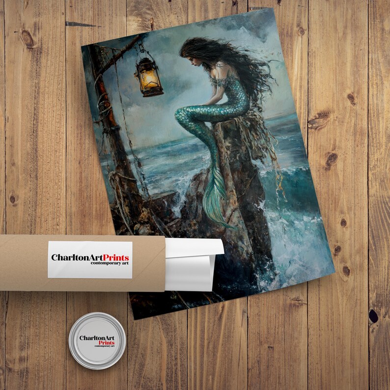 Puede incluir: Una impresi&oacute;n de una sirena con largo cabello negro y cola turquesa, sentada en una roca junto al mar. Una linterna cuelga de una estructura de madera. La impresi&oacute;n es de Charlton Art Prints.