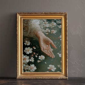May include: A hand reaches out from a pool of water, surrounded by white blossoms. The water is a deep green, and the hand is pale and delicate. The image is framed in a gold frame.