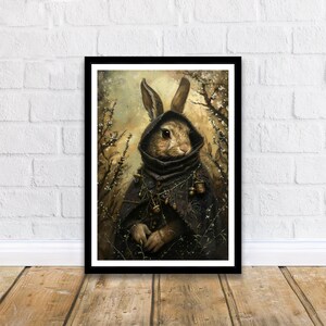 May include: A brown rabbit wearing a dark hooded cloak with a chain and bells hanging from it. The rabbit is standing in a forest setting with a blurred background of trees and foliage.