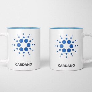 May include: Two white ceramic mugs with a blue interior and a white handle. Each mug features a blue circular design and the word "CARDANO" in black. The design is a series of blue dots arranged in a circular pattern.