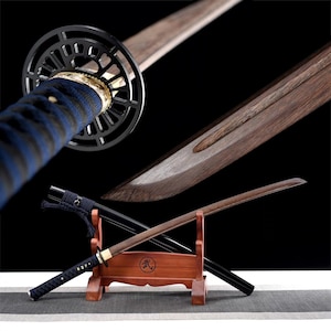 Op de afbeelding: Een zwart en bruin katana zwaard met een blauw en zwart gepatroneerd handvat. Het zwaard staat op een houten standaard met een rode basis. De standaard heeft een kanji-teken erop.