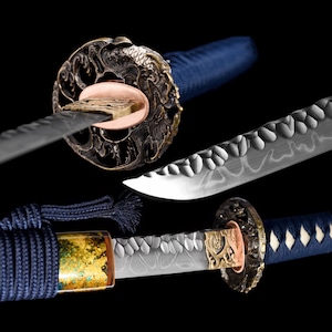 Puede incluir: Una katana japonesa tradicional con un mango azul y dorado y una hoja plateada. La hoja tiene un patrón decorativo y es afilada. La espada es un hermoso ejemplo de la artesanía japonesa.