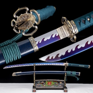 Op de afbeelding: Een katana met een lemmet met een paars en zilverkleurig golfpatroon, een donkergroen met koord omwikkeld handvat en een versierde koperen stootplaat. Het zwaard wordt getoond met de bijpassende donkerblauwe schede op een decoratieve zwarte standaard.