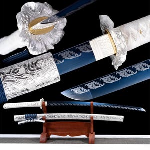 May include: A katana sword featuring a blue blade with a white leaf pattern, a white wrapped handle, and a silver floral tsuba. The scabbard is silver with intricate embossed designs and blue cord accents, displayed on a wooden stand.