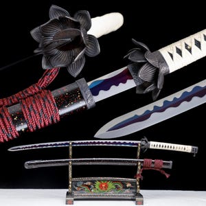 Op de afbeelding: Een katana met een wit omwikkeld handvat en een zwarte lotusvormige stootplaat. Het lemmet heeft een golvende blauwe en paarse hardingslijn. De zwarte schede is gespikkeld met rood en goud en omwikkeld met een rood koord op een standaard.