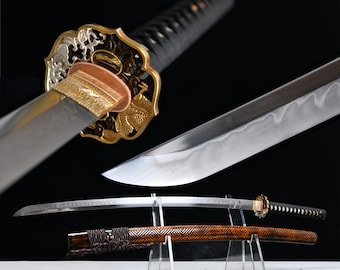 May include: A Japanese katana sword with a curved blade, intricate gold and copper accents, and a black handle. The scabbard is brown with a geometric pattern. The sword is displayed on a clear stand against a black background.