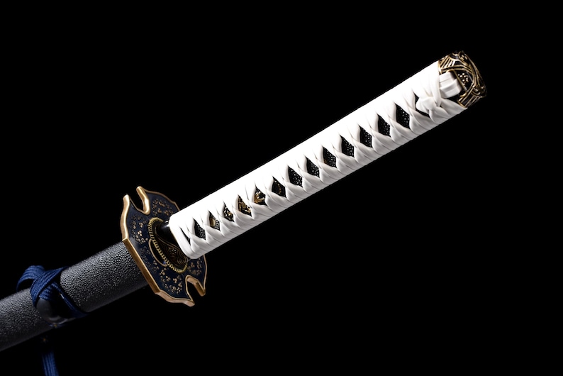 Puede incluir: Una espada katana japonesa con un mango blanco envuelto en un patr&oacute;n de diamantes. La guarda es negra y dorada, y la hoja es negra. La espada est&aacute; sobre un fondo negro.