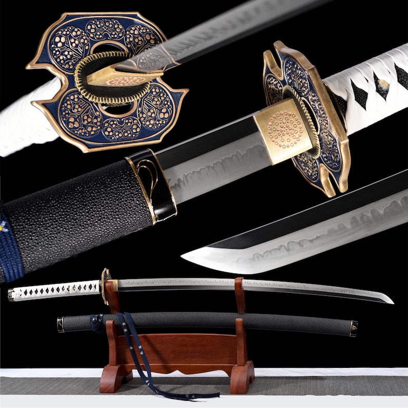 Puede incluir: Una katana ornamentada con una hoja curva, empu&ntilde;adura negra y una guarda decorativa azul y dorada. La espada descansa en un soporte de madera, con una vaina negra y detalles de cord&oacute;n blanco. La hoja es visible, mostrando su filo.