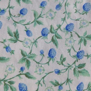 May include: A fabric with a repeating pattern of blue berries and green leaves on a white background. The berries are a vibrant blue, and the leaves are a mix of light and dark green. The design has a watercolor effect.