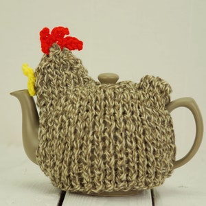 May include: A brown knitted teapot cosy shaped like a chicken with a red comb and yellow beak.