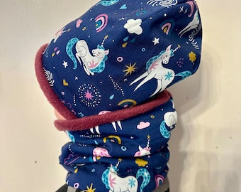 May include: A blue and pink unicorn-themed hat and neck warmer set. The hat is a slouchy beanie style with a fold-over brim. The neck warmer is a long, tube-shaped scarf.