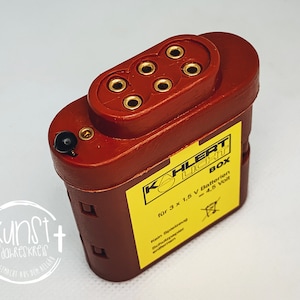 Könnte beinhalten: Eine rote Batteriebox mit einem gelben Etikett, auf dem "KAHLERT LICHT BOX" und "für 3 x 1,5 V Batterien = 4,5 Volt" steht.