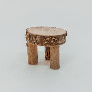 Könnte beinhalten: Ein kleiner Holztisch mit runder Tischplatte und drei Beinen. Der Tisch ist aus Naturholz gefertigt und hat einen rustikalen Look.
