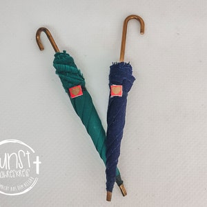 Peut inclure: Deux mini parapluies avec des poignées dorées. Un parapluie est vert et l'autre est bleu. Les deux parapluies ont un autocollant en forme de cœur rouge.