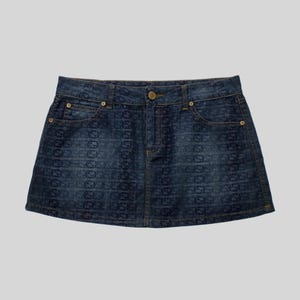May include: A denim mini skirt with a dark blue wash. The skirt features a repeating pattern of a logo. It has a button and zipper closure, along with two front pockets and two back pockets. The skirt is a classic, casual style.