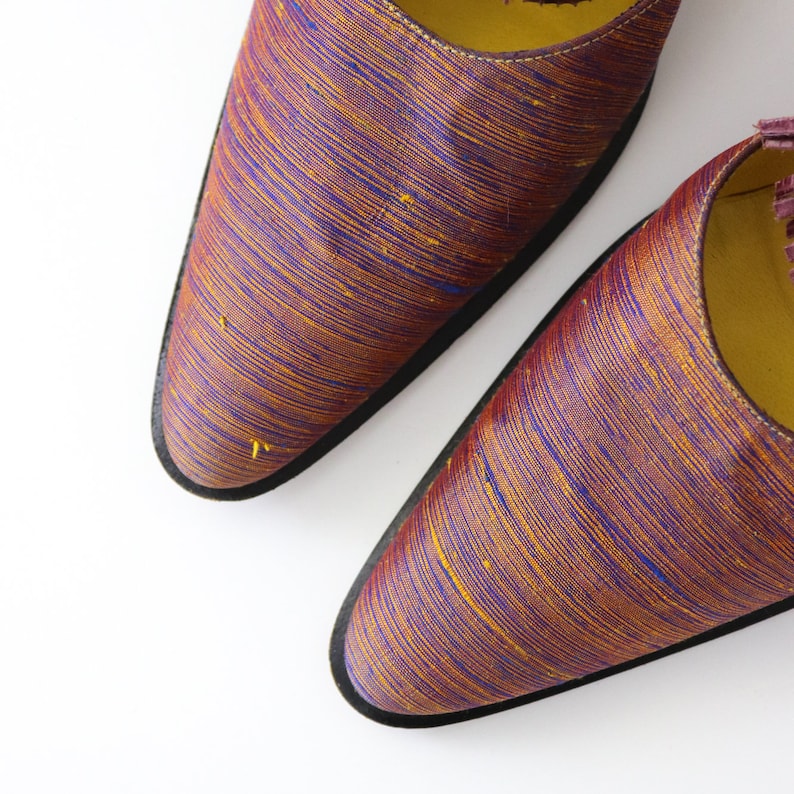 K&ouml;nnte beinhalten: Ein Paar spitze Schuhe mit einem Obermaterial aus burgunderfarbenem und goldenem gestreiftem Stoff. Die Schuhe haben eine schwarze Sohle.