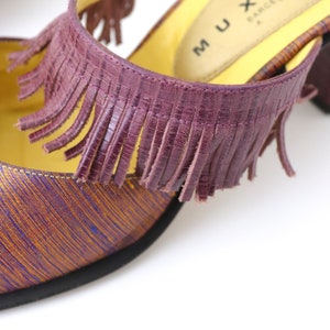 K&ouml;nnte beinhalten: Lilafarbener Lederfransen-Detail an einem gelb-violetten gemusterten Schuh mit dem Text "MUX BARCELONA" auf der Innensohle.