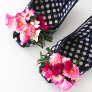 May include: A pair of black and white gingham peep-toe heels with pink and white flower embellishments.