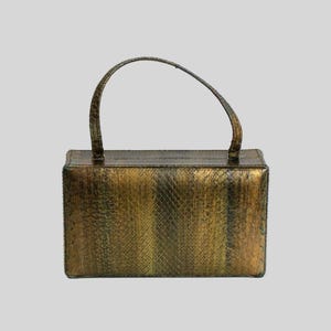 May include: A rectangular handbag with a single arched handle. The bag has a textured, snakeskin-like pattern in shades of gold and brown. The handle is a matching color and texture.