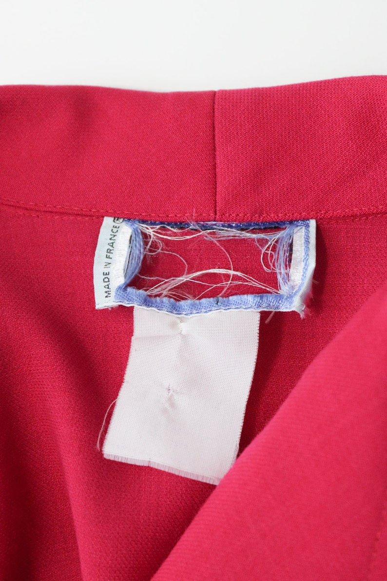 May include: A close-up of a red fabric garment with a white tag that says "Made in France".